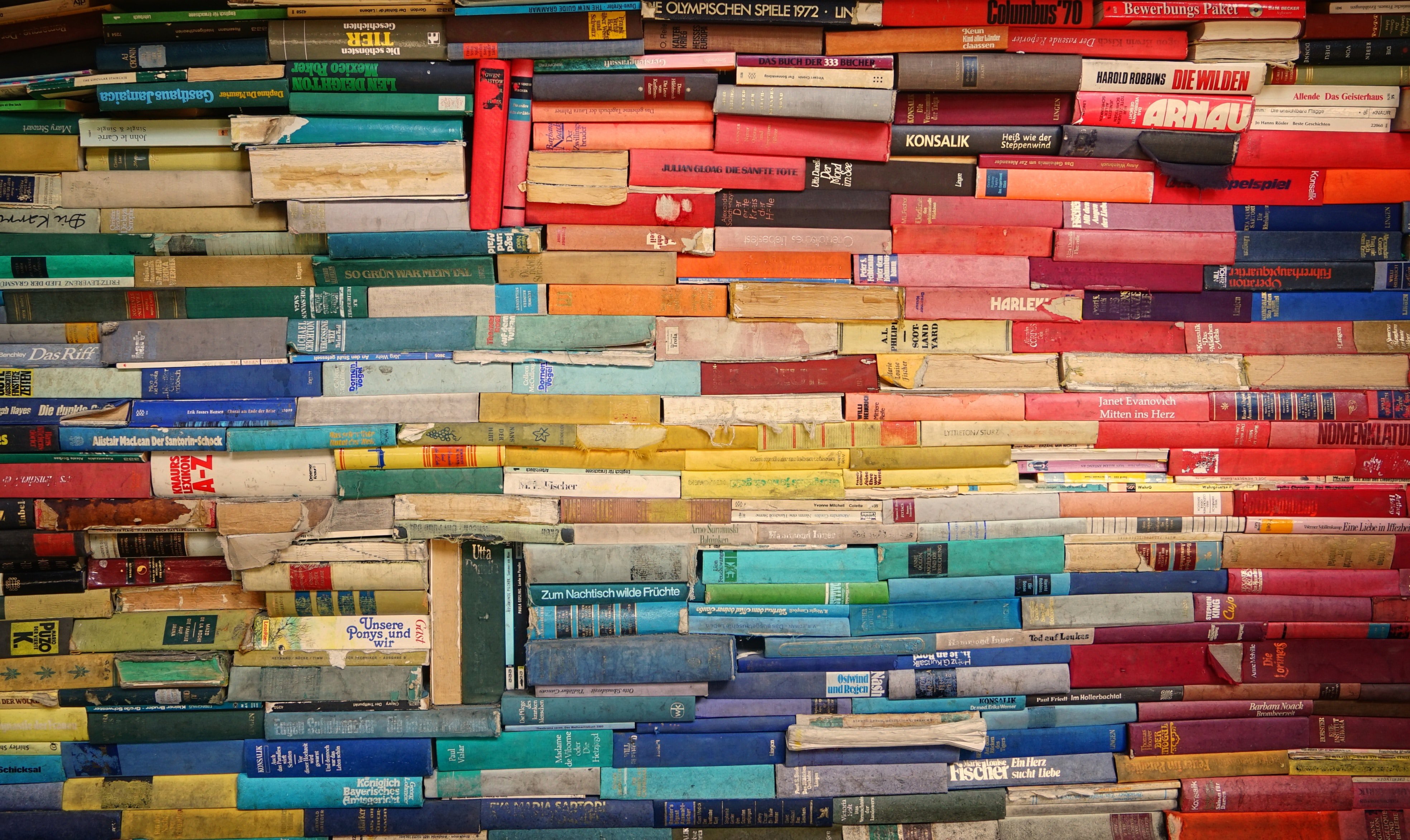 Books neatly arranged in a pile against a wall, representing a wealth of information and intellectual exploration.